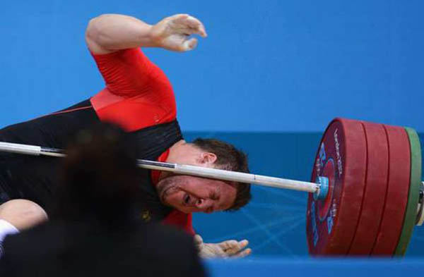 A man face plants while lifting a barbell in a weightlifting competition.