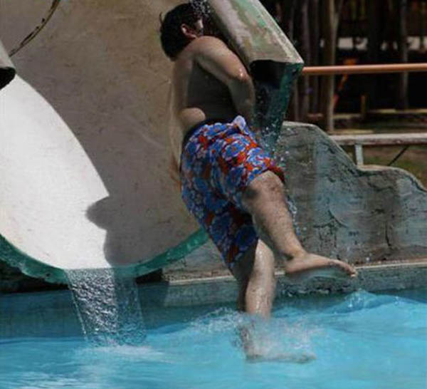 A man is sliding down a water slide at a water park, but he unfortunately 