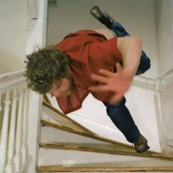 A man falling down a set of stairs and face planting.