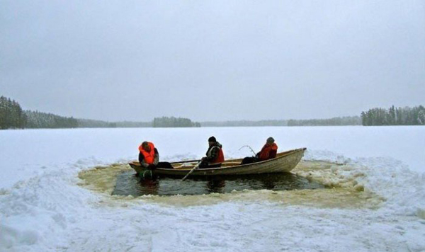 Two people in a canoe on a frozen Russian lake during fishing season.