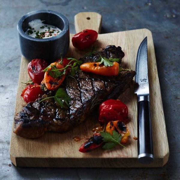 Let’s Eat! A steak on a cutting board with tomatoes and a knife.