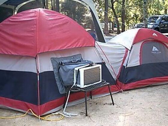 A radass camping tent equipped with an air conditioner and a cooler.