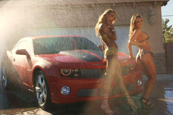 Two women in bikinis, the perfect combination, standing next to a red car.