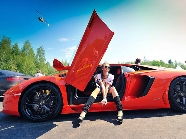 A woman sitting next to a red sports car showcasing The Perfect Combination of style and power.