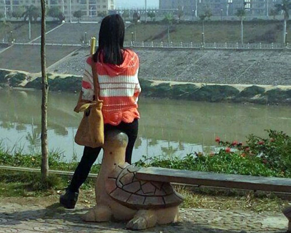 A woman sitting on a bench next to a statue.