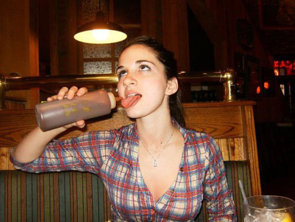 A woman in a plaid shirt enjoying a chocolate milkshake.