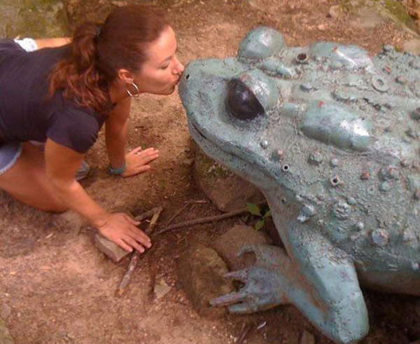 A woman affectionately kisses an unusual statue, perplexed by her attraction.