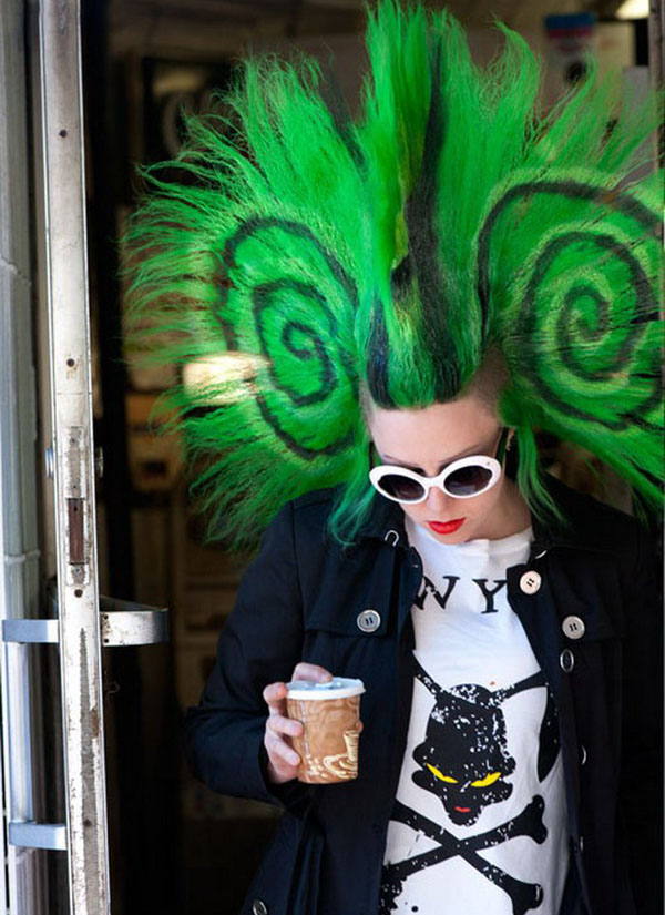 A woman with green hair holding a cup of coffee, making her look effortlessly stylish and intriguing.