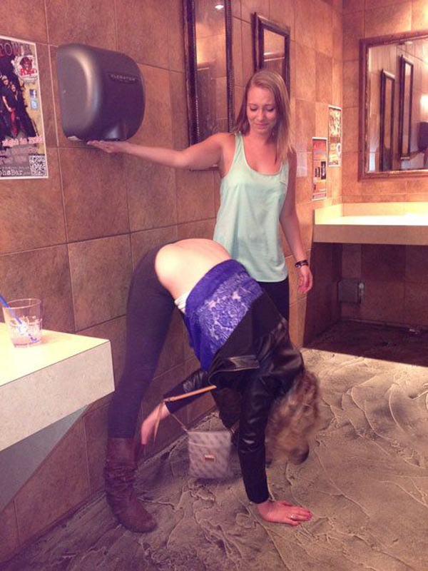 A woman is doing a handstand in a bathroom, showcasing impressive flexibility and balance.
