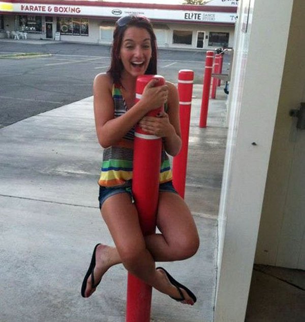 A girl sitting on top of a crimson pole.