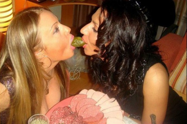 Two women kissing in front of a plate of meat that makes one hesitant to date.