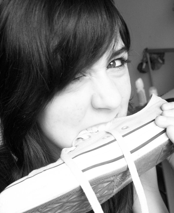 A black and white photo of a girl with a shoe in her mouth, expressing the humorous phrase 