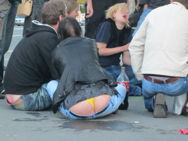 A group of people sitting on the ground, exposing their bare buttocks.