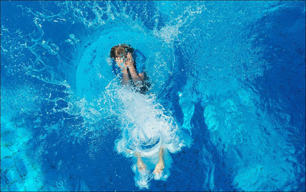 A woman is swimming in a beautiful blue pool.