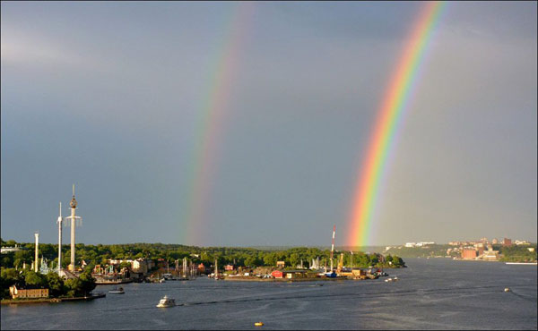A breathtaking double rainbow creates a stunning scene over a body of water, showcasing the beauty of the world.