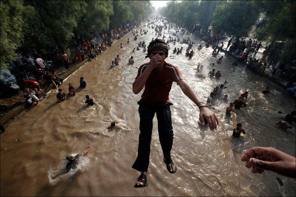 A man floats in a flooded street, capturing the beauty of the world amidst chaos.