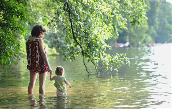 A heartwarming image capturing a woman and a child enjoying the serene beauty of a lake.