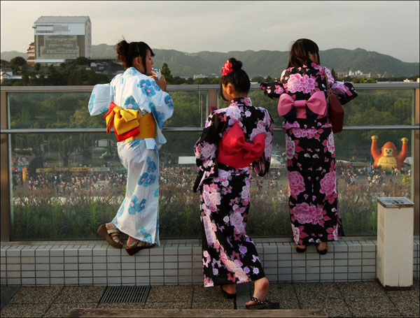 Three women in beautiful kimono standing on a balcony in this stunning world.