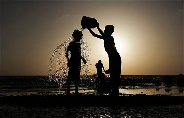 A beautiful silhouette of a couple splashing water on the beach.