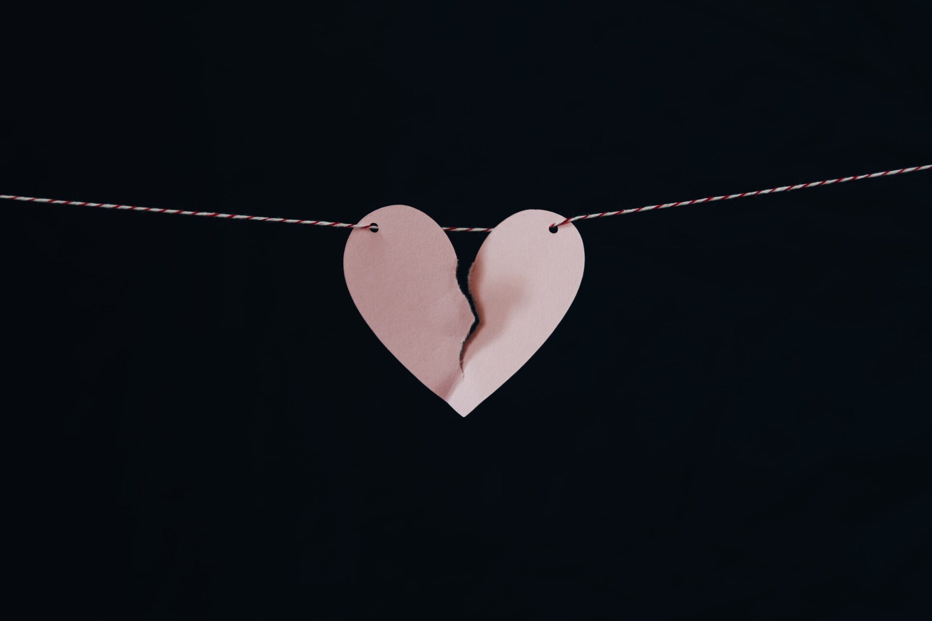 Hilariously portrays a broken heart on a string against a black background.