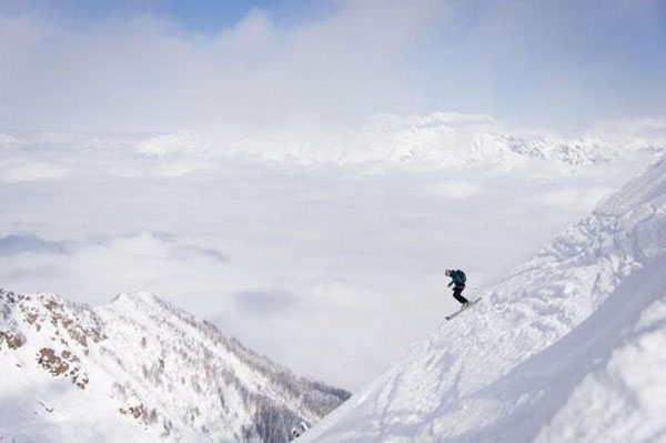 A skier is skiing down a mountain covered in snow, experiencing the awesome beauty of life.