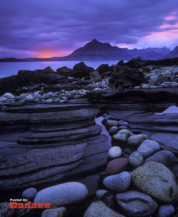 A rocky shore with majestic mountains in the background is what a wonderful world.