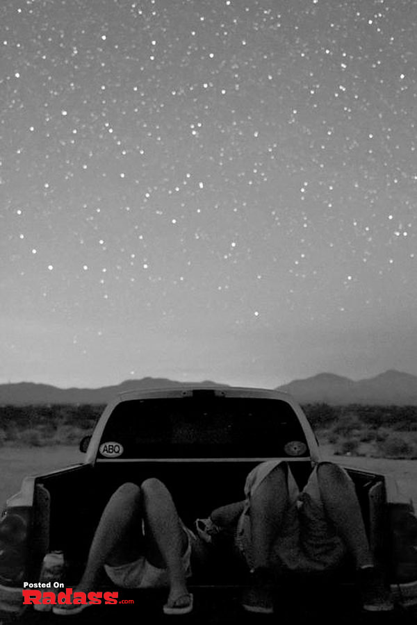 Two people sitting in the back of a truck, thinking to themselves under the stars in this wonderful world.
