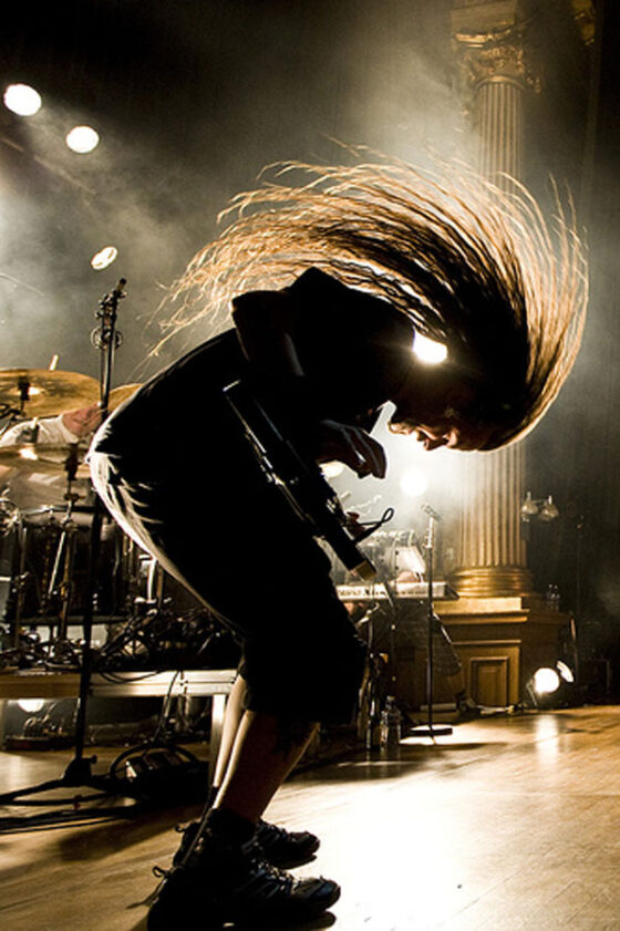 A human with long hair captivating the audience on a stage.