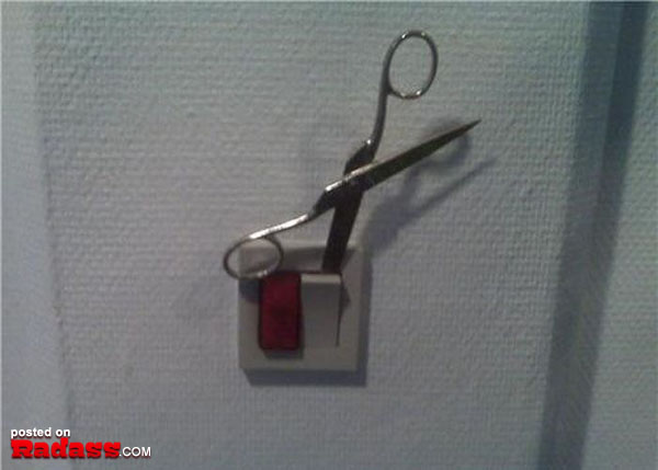 A pair of scissors is attached to a light switch in this intriguing combination.