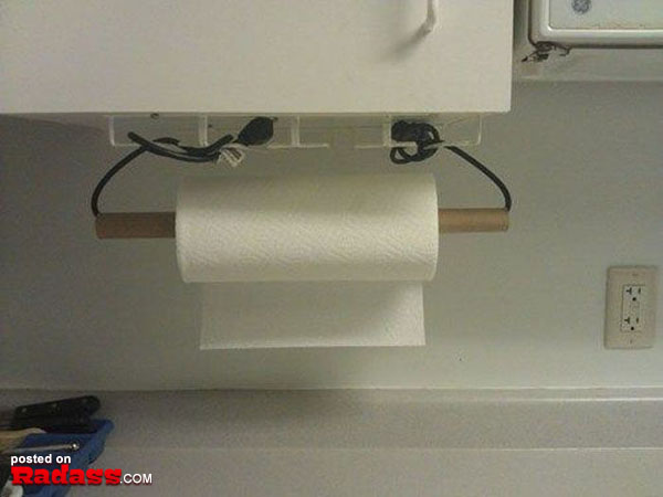 A toilet paper holder with wires hanging from it, perfect for those times when you need one of the 50 Redneck Remedies to help you out.