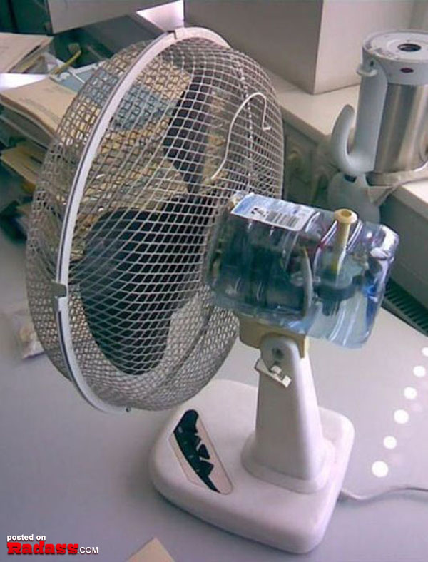 A fan is sitting on a table next to a bottle of water, providing relief in times of heat.