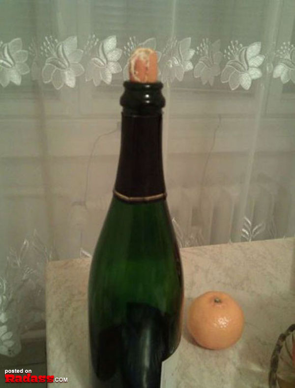 A bottle of champagne sitting on a counter next to an orange, offering a touch of elegance and refreshment.