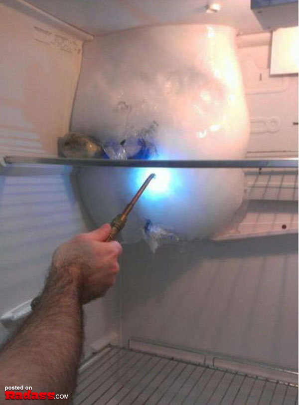 A person is using a tool to remove ice from an open refrigerator using one of the 50 Redneck Remedies To Help You In Times Of Need.