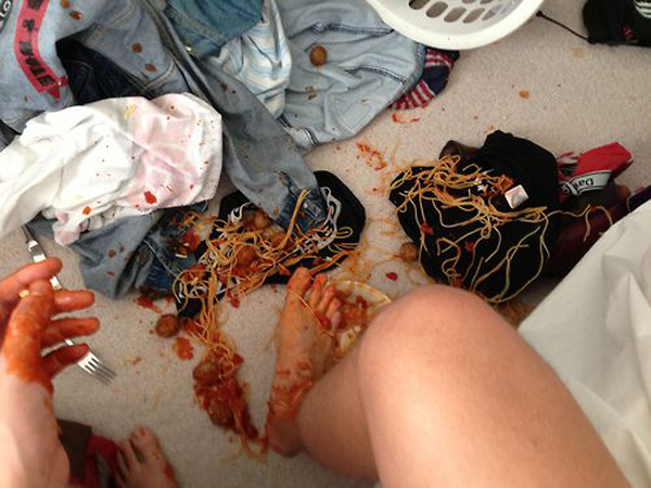 A person's feet are covered in spaghetti, showcasing a smile during this humorous moment.