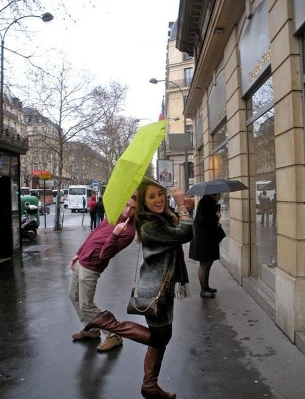 A man and a woman holding an umbrella in the rain, despite Trolls Live to Piss You Off.