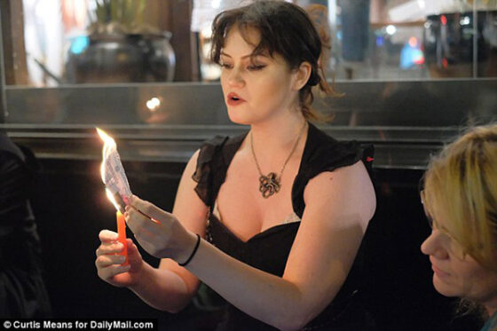 A woman holding a candle in front of a group of people during Lana Del Rey's "Witches Spell.