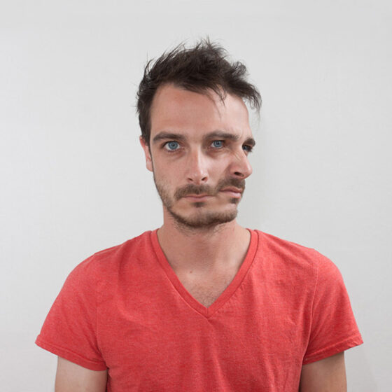 A man in a red t-shirt, engulfed in the inner struggle between two senses, adorned with a fake face.