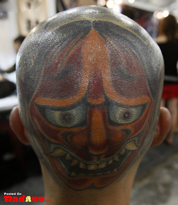 A man's head tattooed with an asian mask showcasing the concept of permanence.