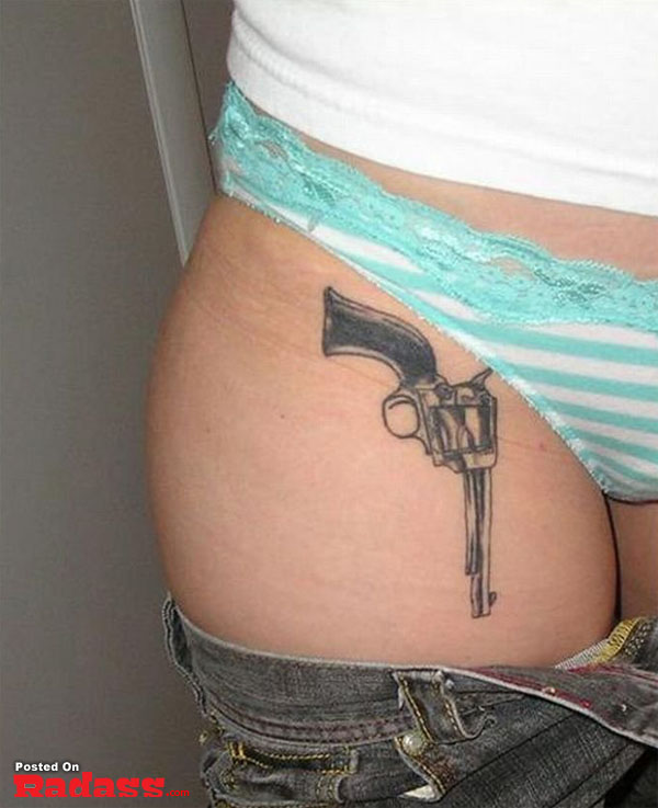 A woman packing a gun tattoo on her thigh.