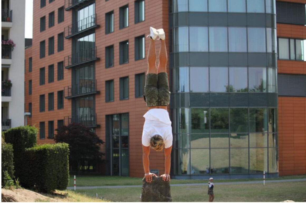 A man performing calisthenics in front of a building.