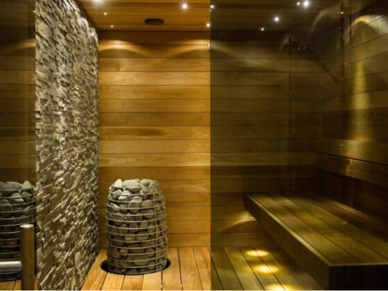A sauna room with wooden walls and a stone bench provides a cool and relaxing retreat, even amid COVID.