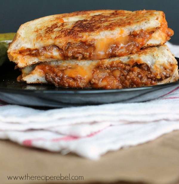 A comforting grilled cheese with chili and pickles on a plate.