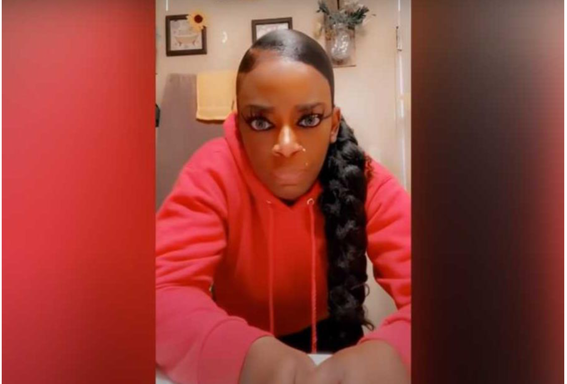 A woman in a red hoodie takes a selfie, questioning if it will bring her clout like the Gorilla Glue Girl and her bad decision.