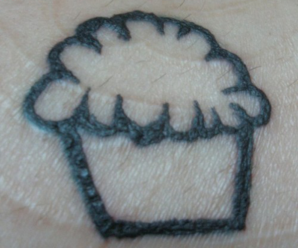 A regrettable tattoo of a cupcake on a person's wrist.