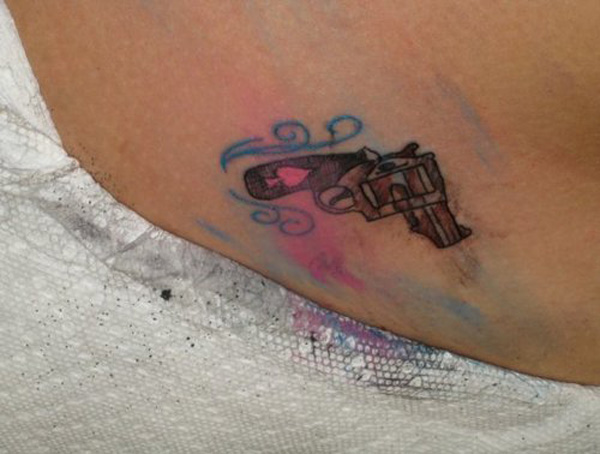 A gun tattoo serves as a permanent reminder of a regrettable choice on a woman's back.