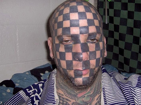 A man with a forever reminder of bad decisions, his face covered in tattoos.