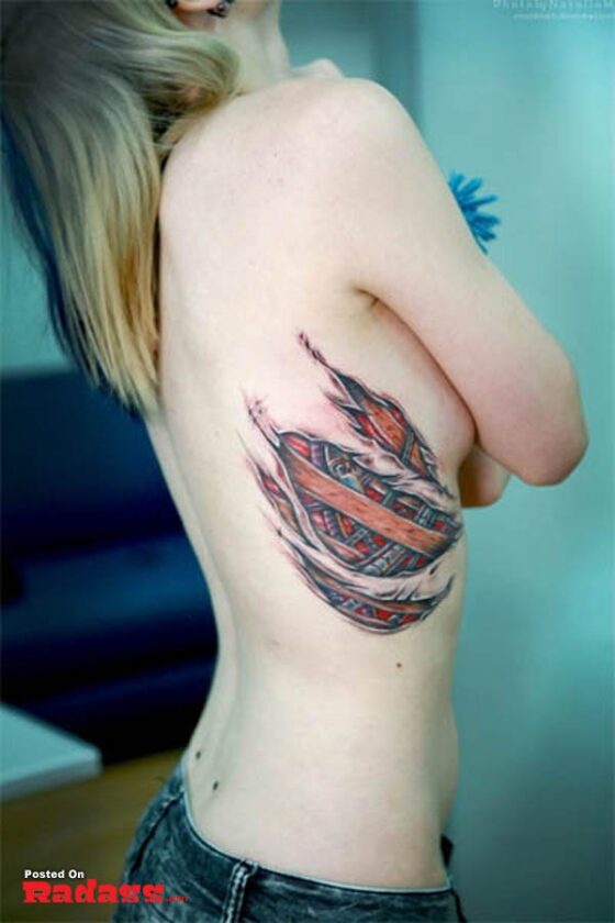 A woman with a realistic feather tattoo on her ripped back.