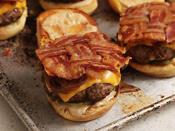 Warning: Bacon-wrapped burgers on a baking sheet showcasing food porn.