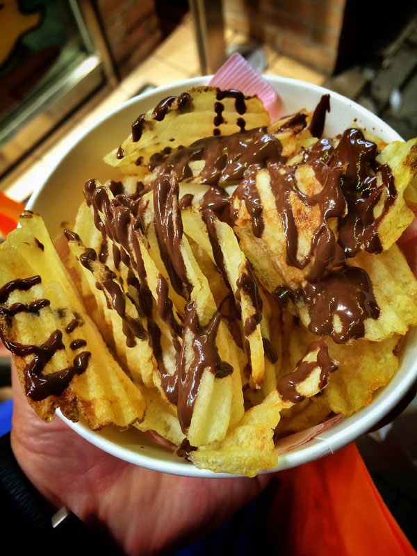 A person holding a bowl of indulgent chocolate-dipped fries, a perfect example for 