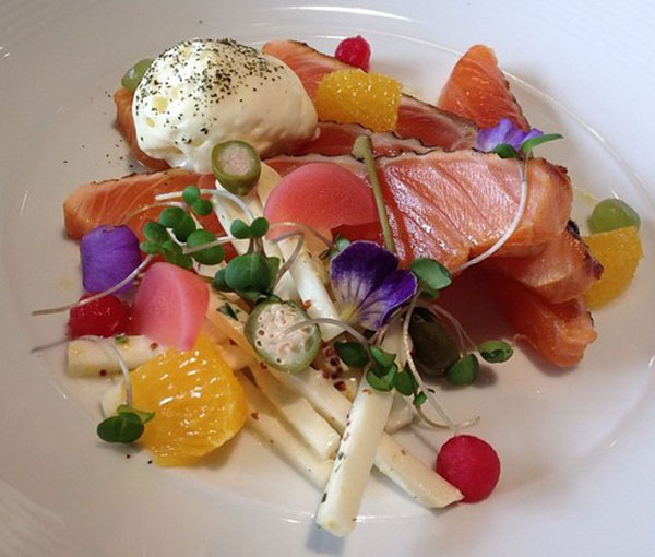 A plate featuring a tempting arrangement of salmon, oranges, and creme fraiche.